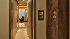 A hallway with wooden doors marked 402 and 403, leading to a room with a chair and a window. - Sayaji Rajkot (Rajkot)