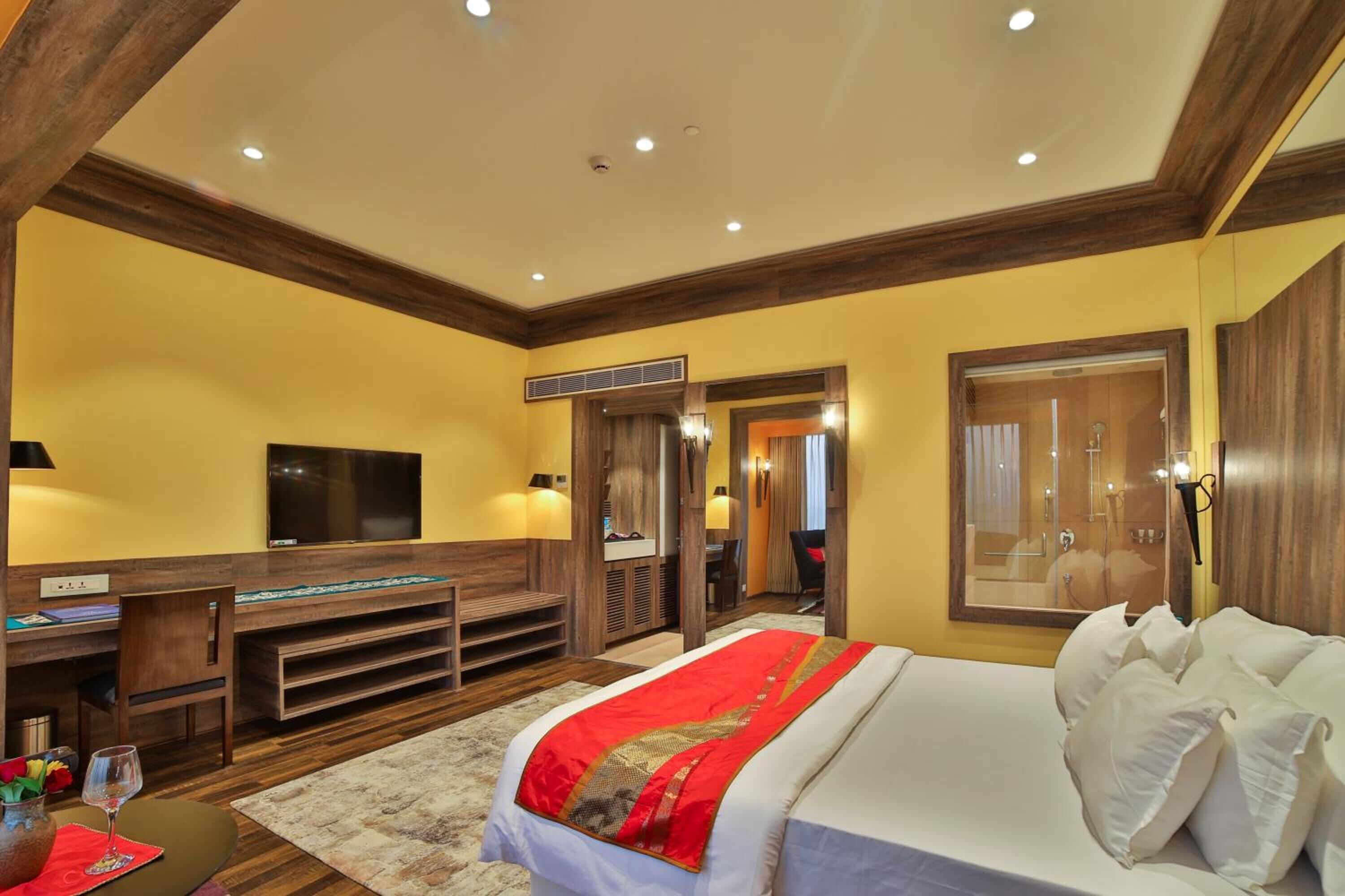 Une chambre d’hôtel avec un grand lit, un bureau avec un ordinateur, une télévision et un miroir.