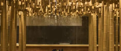 Ein Restaurant mit einem langen Tisch, gedeckt zum Essen, umgeben von hohen Bambusstützen und einem großen Fenster im Hintergrund.