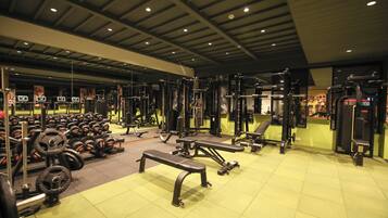Un gimnasio con varios equipos de ejercicio, incluyendo bancos, mancuernas y máquinas de pesas.