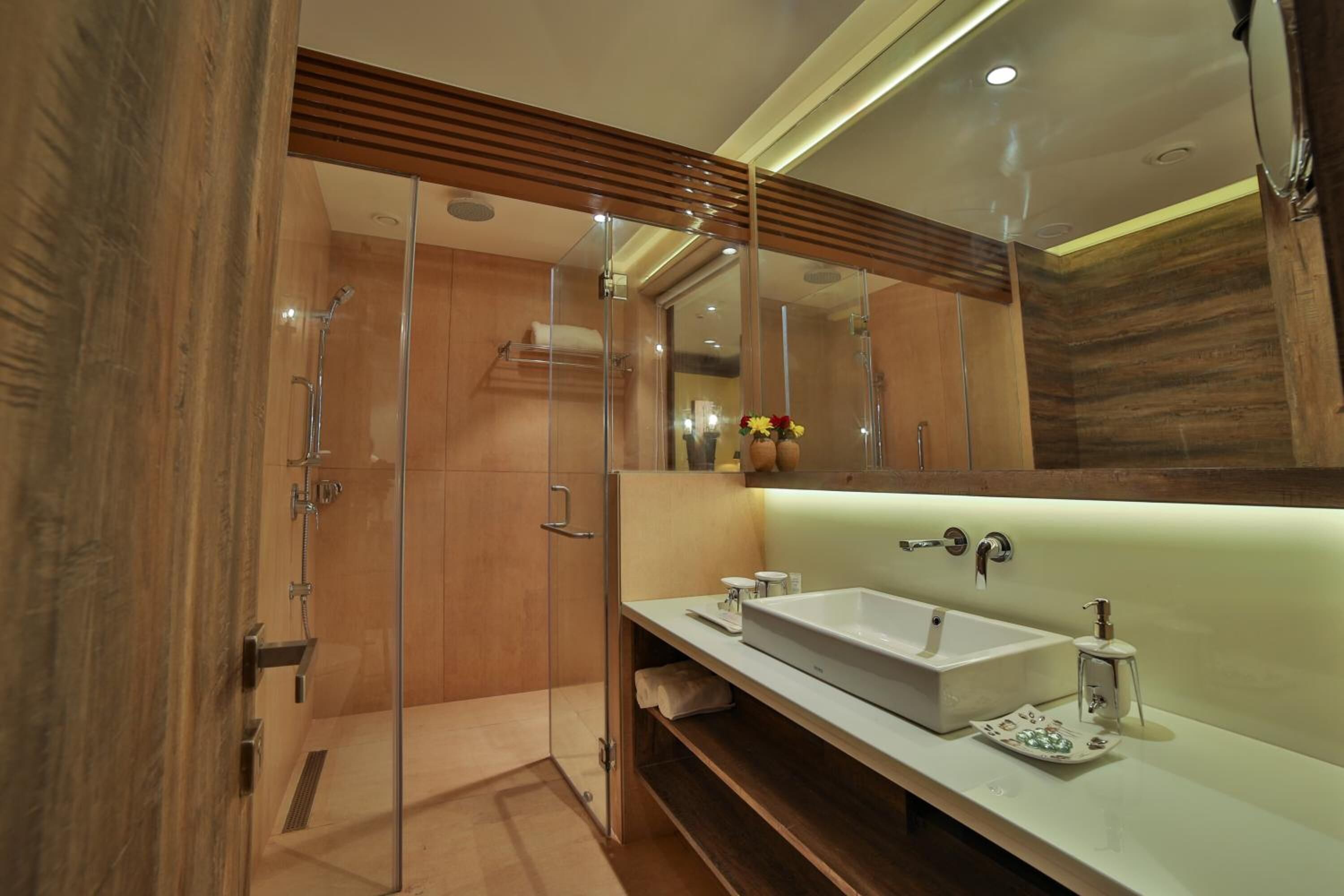 A modern bathroom with a glass-enclosed shower, a large mirror, and a white sink.