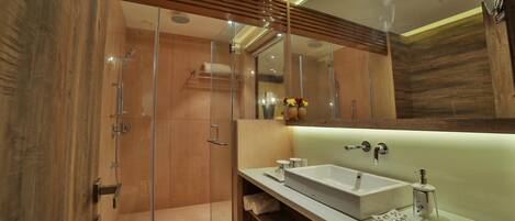 A modern bathroom with a glass-enclosed shower, a large mirror, and a white sink.