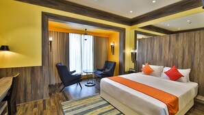 A hotel room with a large bed, a desk, a chair, and a small table.