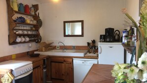 Una cocina compacta con armarios de madera, horno empotrado, lavavajillas y cafetera.