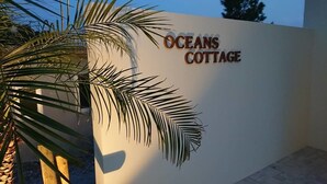 Un letrero de Oceans Cottage con palmeras al frente.