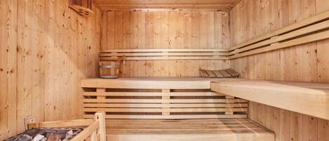 Una sauna de madera con bancos y un elemento calefactor de piedra.