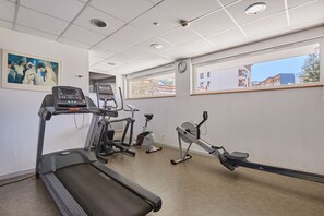 Un gimnasio con cintas de correr, bicicletas estáticas y una máquina de remo.