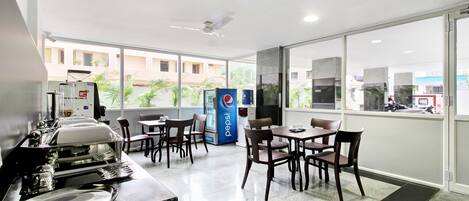 A modern dining area with tables and chairs, a Pepsi refrigerator, and a view of the outside.