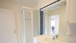 Une salle de bain avec une douche, un lavabo et un miroir.