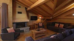A cozy living room with a fireplace, wooden beams, and comfortable seating.
