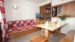 A compact living space with a sofa, a dining table, and a television. - Super endroit ! Appartement avec cuisinette (Tignes)