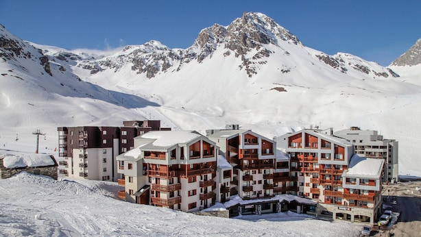 A snow-covered mountain resort with multi-story buildings featuring balconies and ski slopes in the background. - Super endroit ! Appartement avec cuisinette (Tignes)