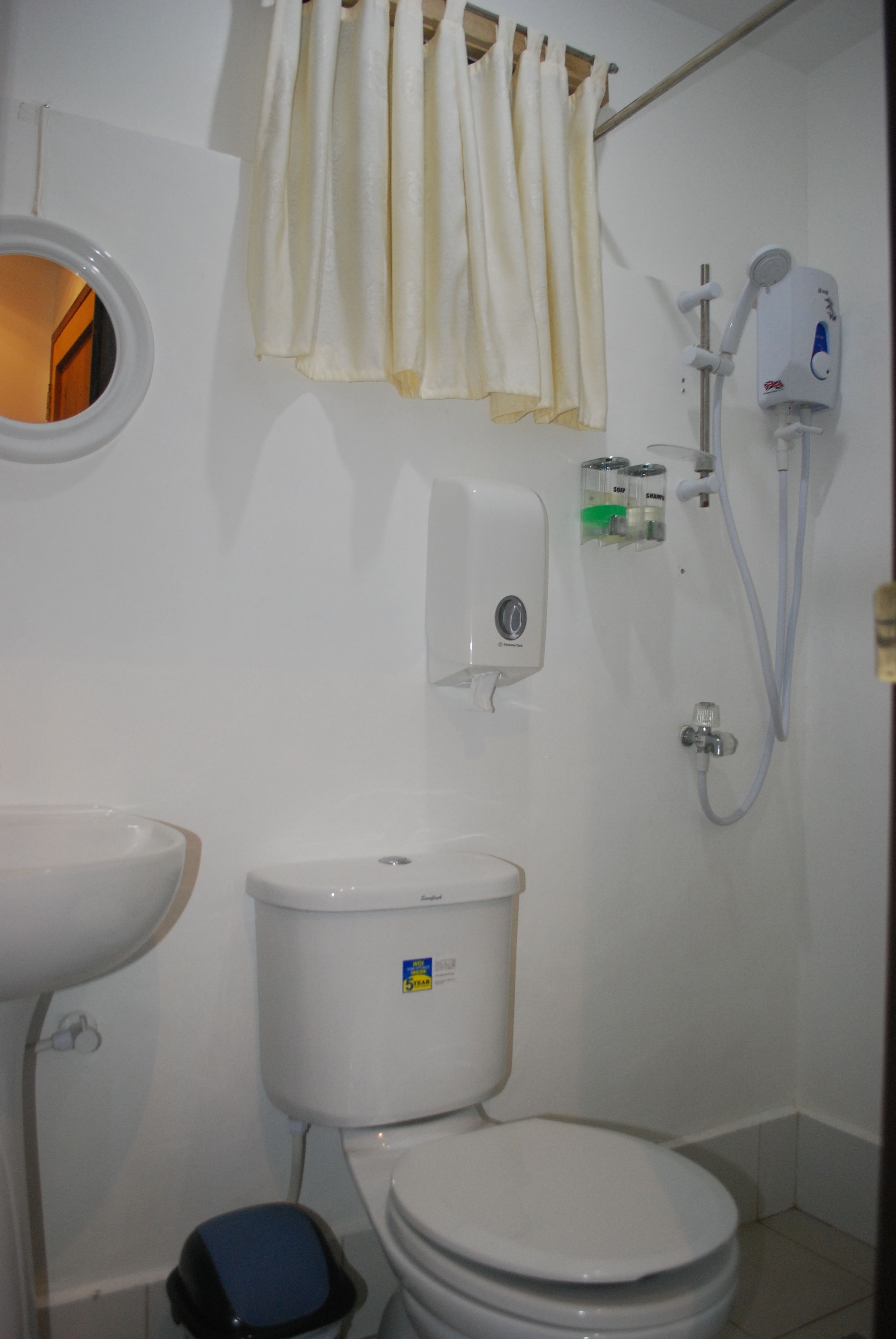 A small bathroom with a toilet, a sink, and a shower.