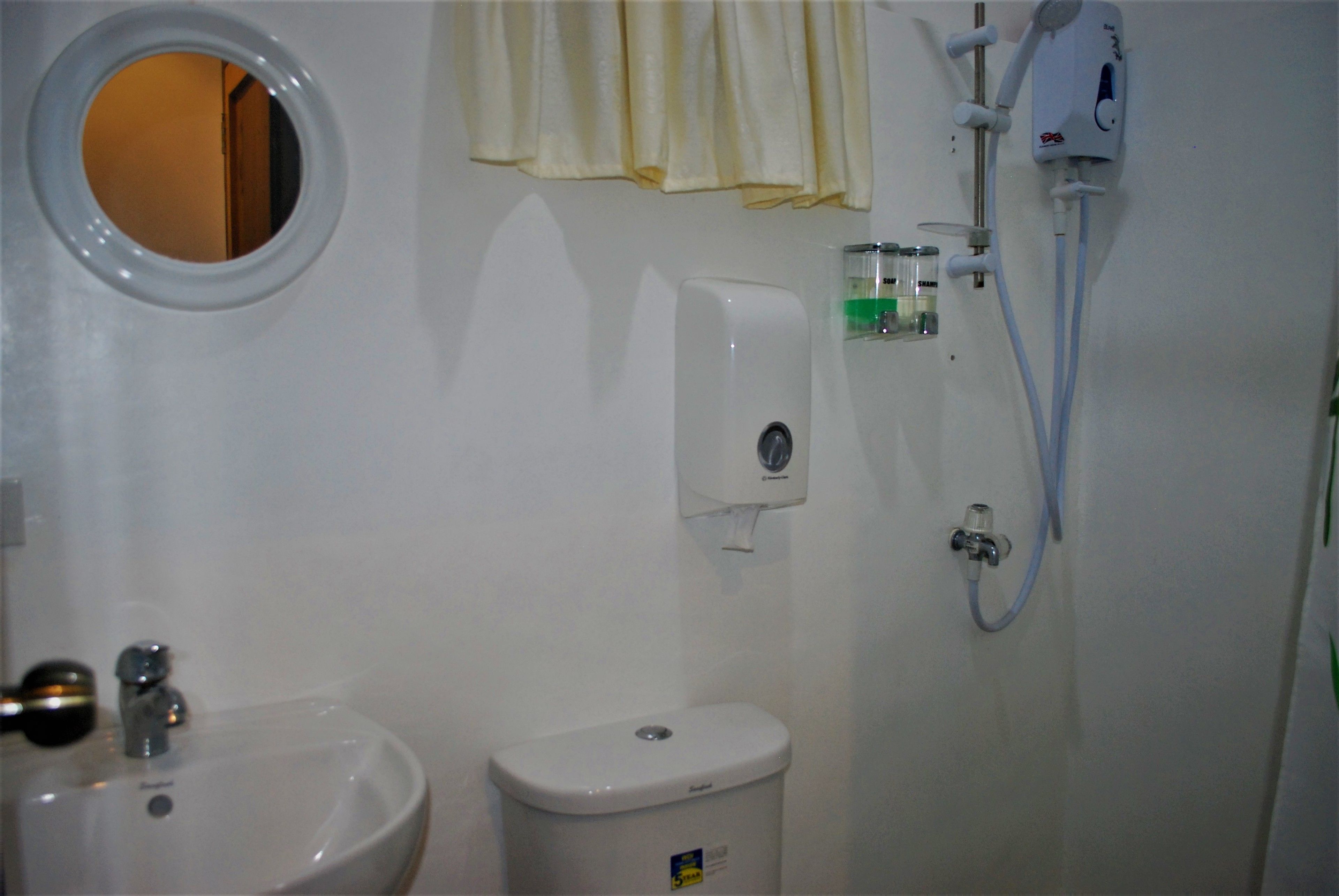 A bathroom with a sink, toilet, and a hand dryer.