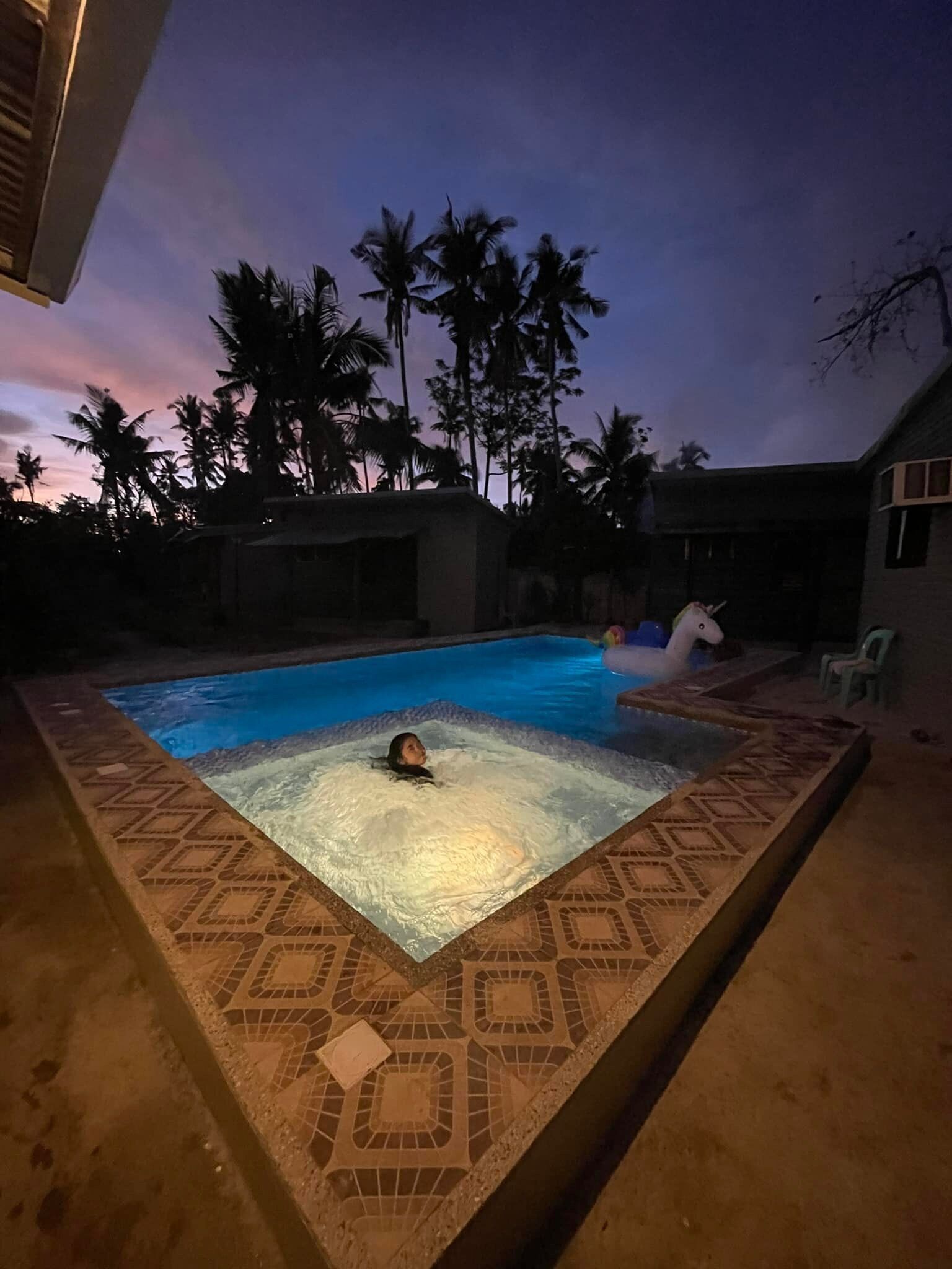 A swimming pool with a tiled border and a person in the water.