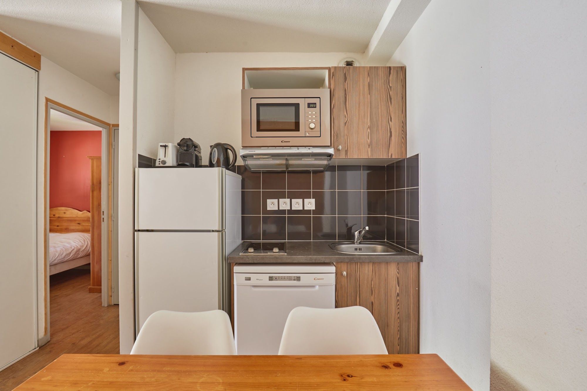 Una kitchenette compacta con microondas, tostadora y lavavajillas.
