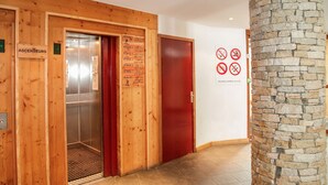 A hotel lobby with wooden paneling, a reception desk, and a stone pillar. - Studio cosy 200m des remontées mécaniques! (Tignes)