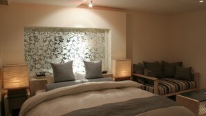 Un dormitorio con una cama, una mesita de noche, una lámpara, un sofá y un panel decorativo en la pared.