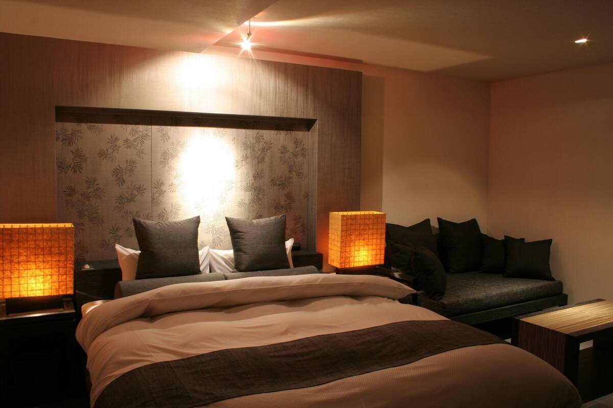 A modern bedroom with a large bed, two bedside tables, a sofa, and a nightstand.