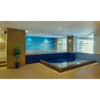 Una piscina interior moderna con una barrera de vidrio, una planta en maceta y una pared con azulejos azules.