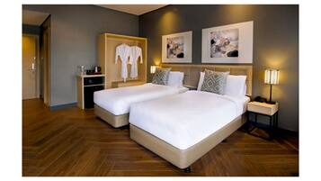 Ein Hotelzimmer mit zwei Betten, einem Kleiderschrank, Bildern an der Wand und Nachttischlampen.