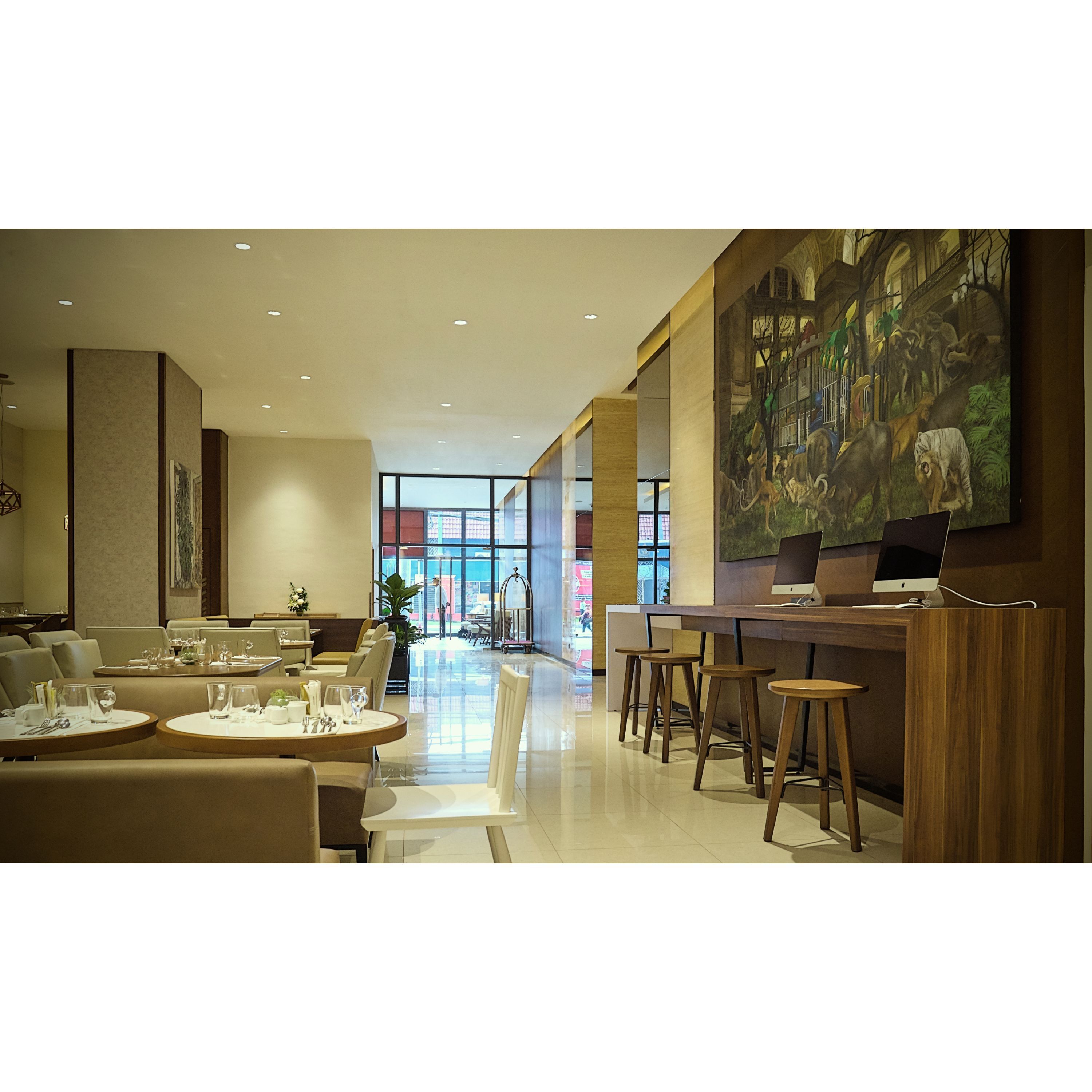 Un hall d’hôtel moderne comprenant un espace repas, un bar et une grande fresque murale.