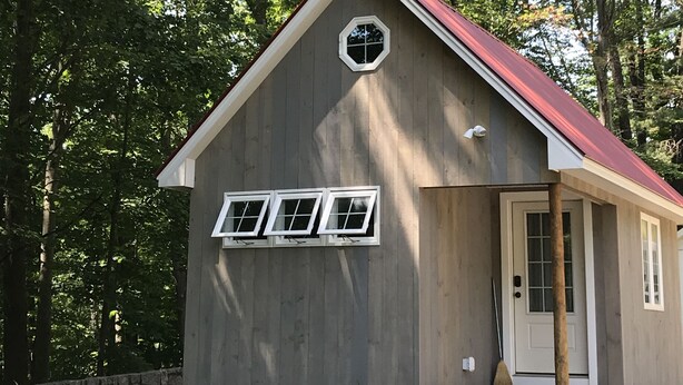 A two-story house with a flat roof, a small circular window on the second floor, and a door with a window on the ground floor. - The in town cabin  (Conway)