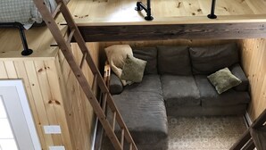 A loft-style bedroom with a bunk bed and a sofa bed, wooden flooring, and a skylight. - The in town cabin  (Conway)