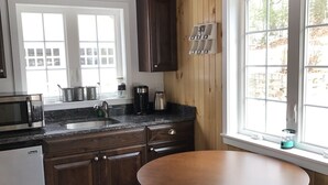 A kitchen with wooden cabinets, a built-in oven, a sink, and a window with a view of the outdoors. - The in town cabin  (Conway)