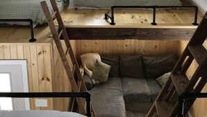 A small attic bedroom with a sloped ceiling, a skylight, a bunk bed, and a wooden ladder. - The in town cabin  (Conway)