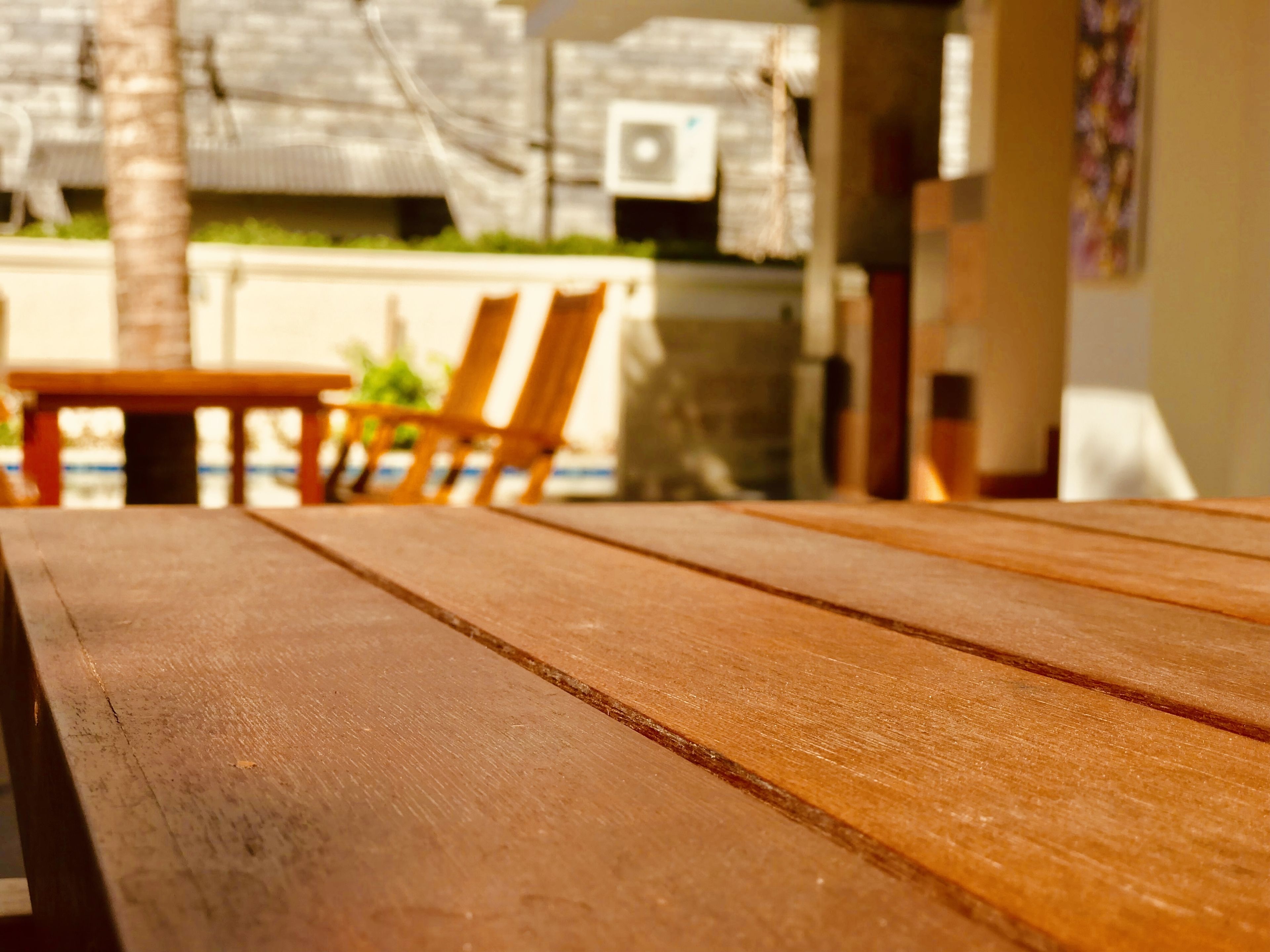 Una mesa de madera con vistas a un área de estar exterior y una piscina al fondo.
