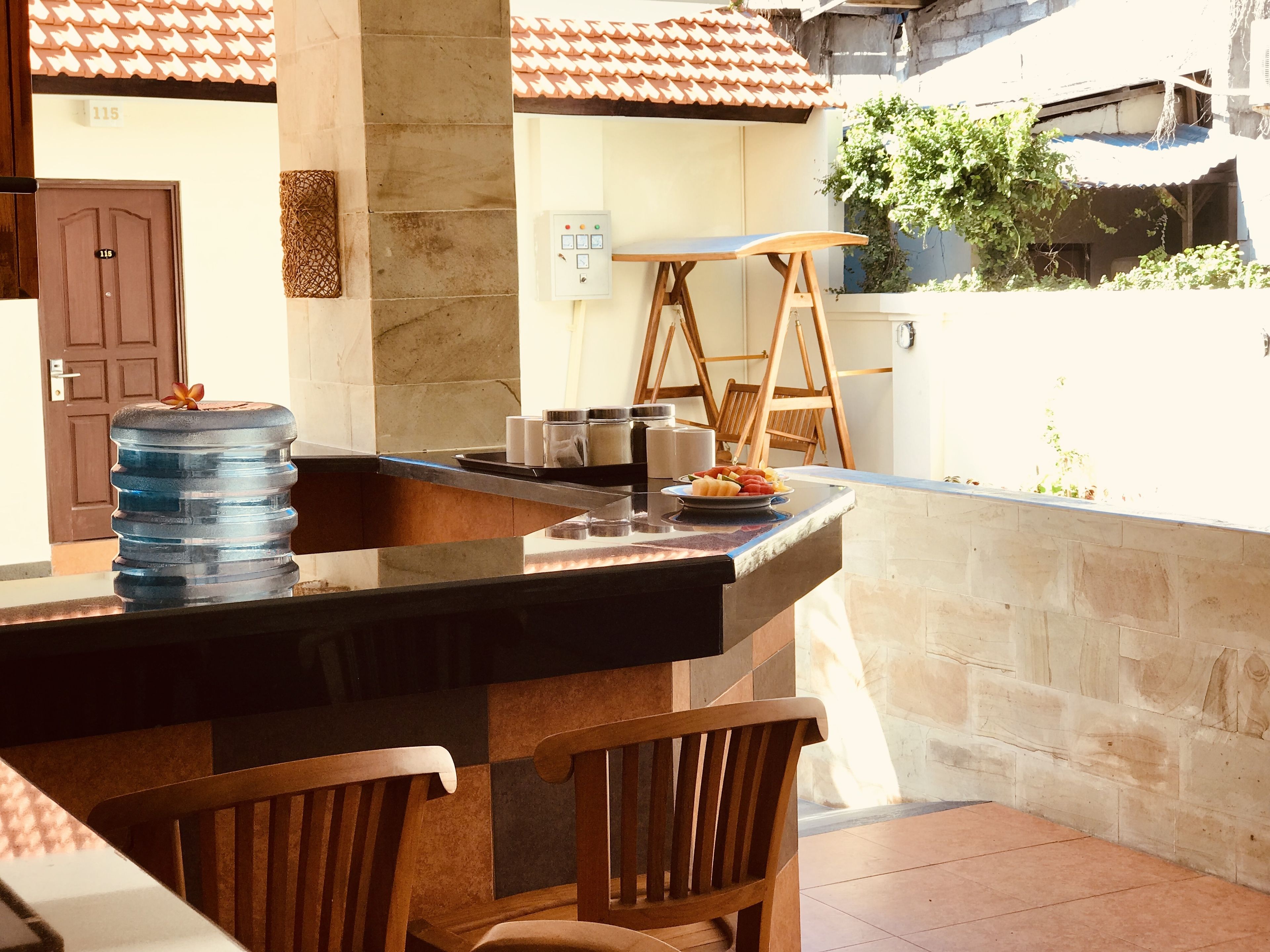 A kitchen area with a large water dispenser, a wooden chair, and a counter with a plate of fruit.