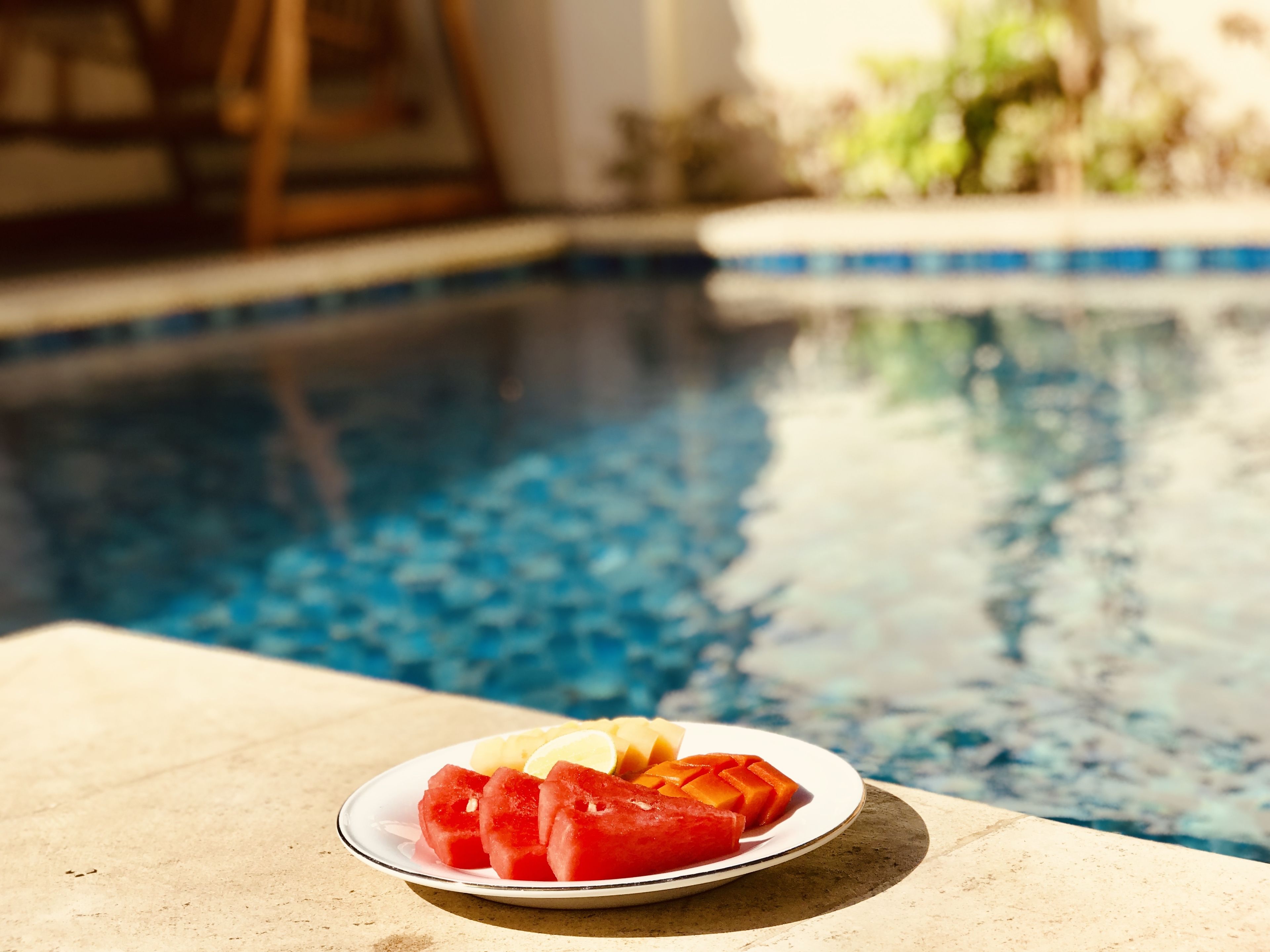 A poolside table with a plate of watermelon and lemon slices.