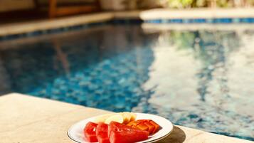 A poolside table with a plate of watermelon and lemon slices.