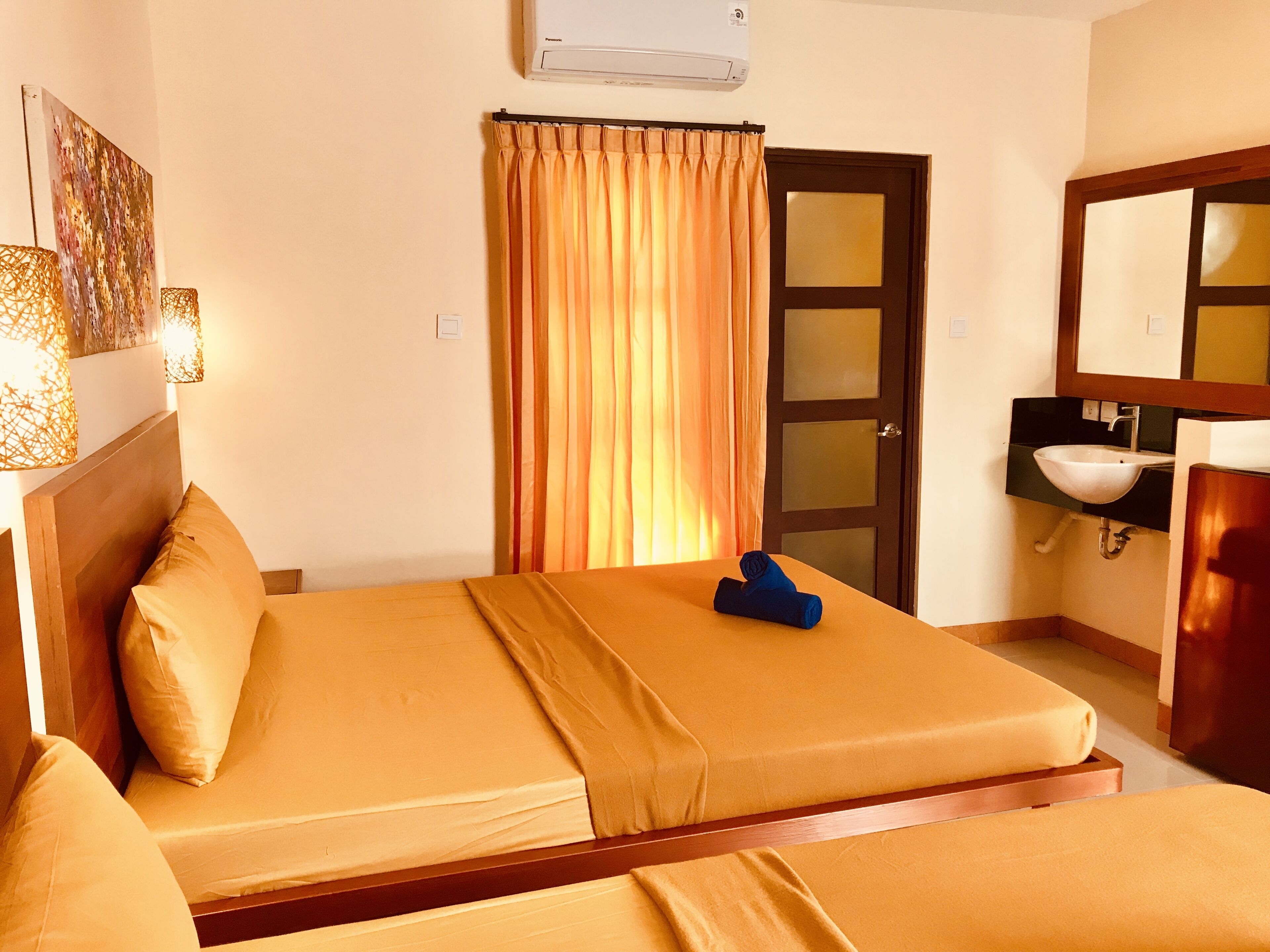 A hotel room with a bed, a bathroom with a sink and mirror, and a door with glass panels.