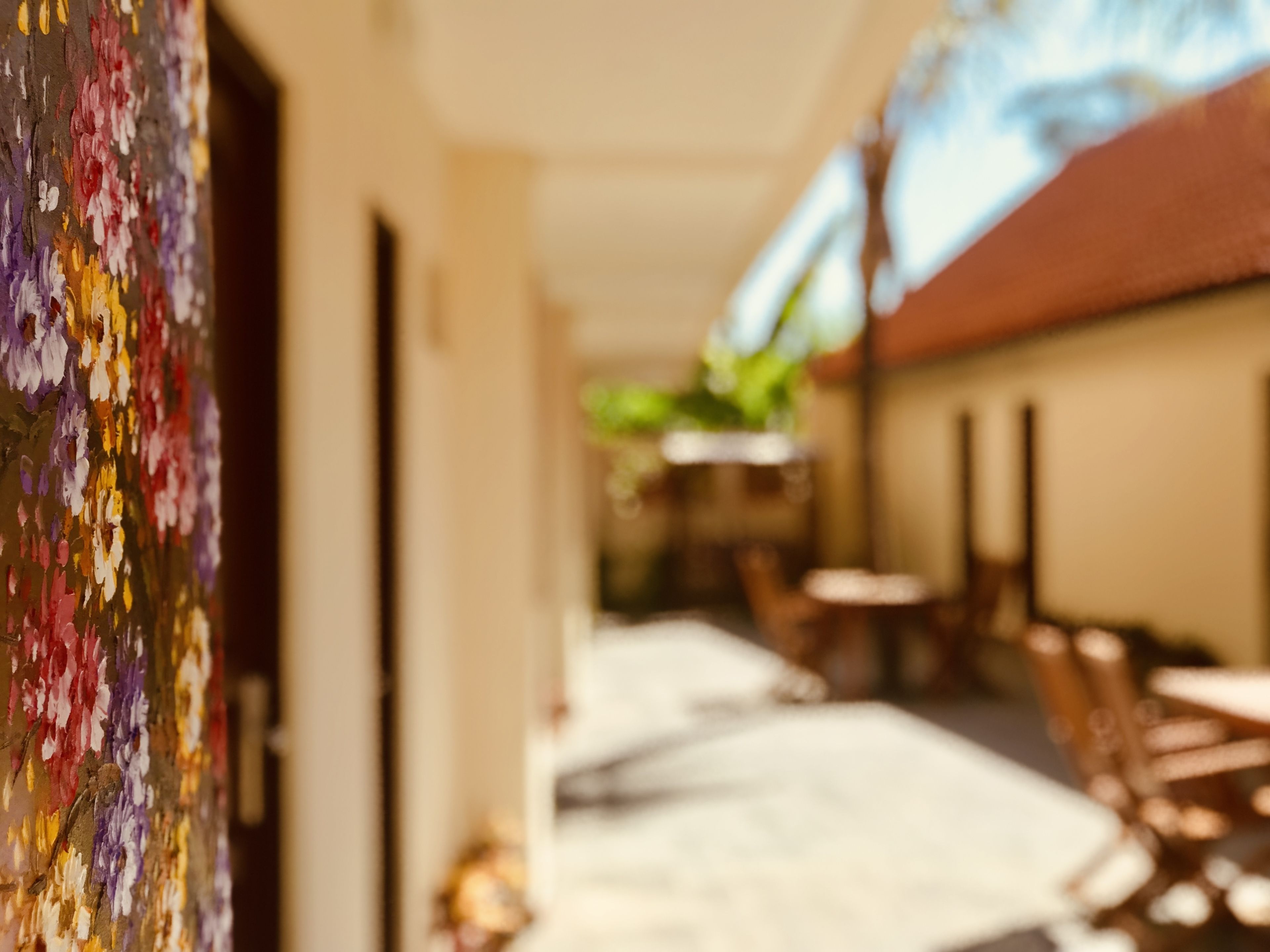 A corridor with a colorful mural on the left, leading to a seating area with tables and chairs.