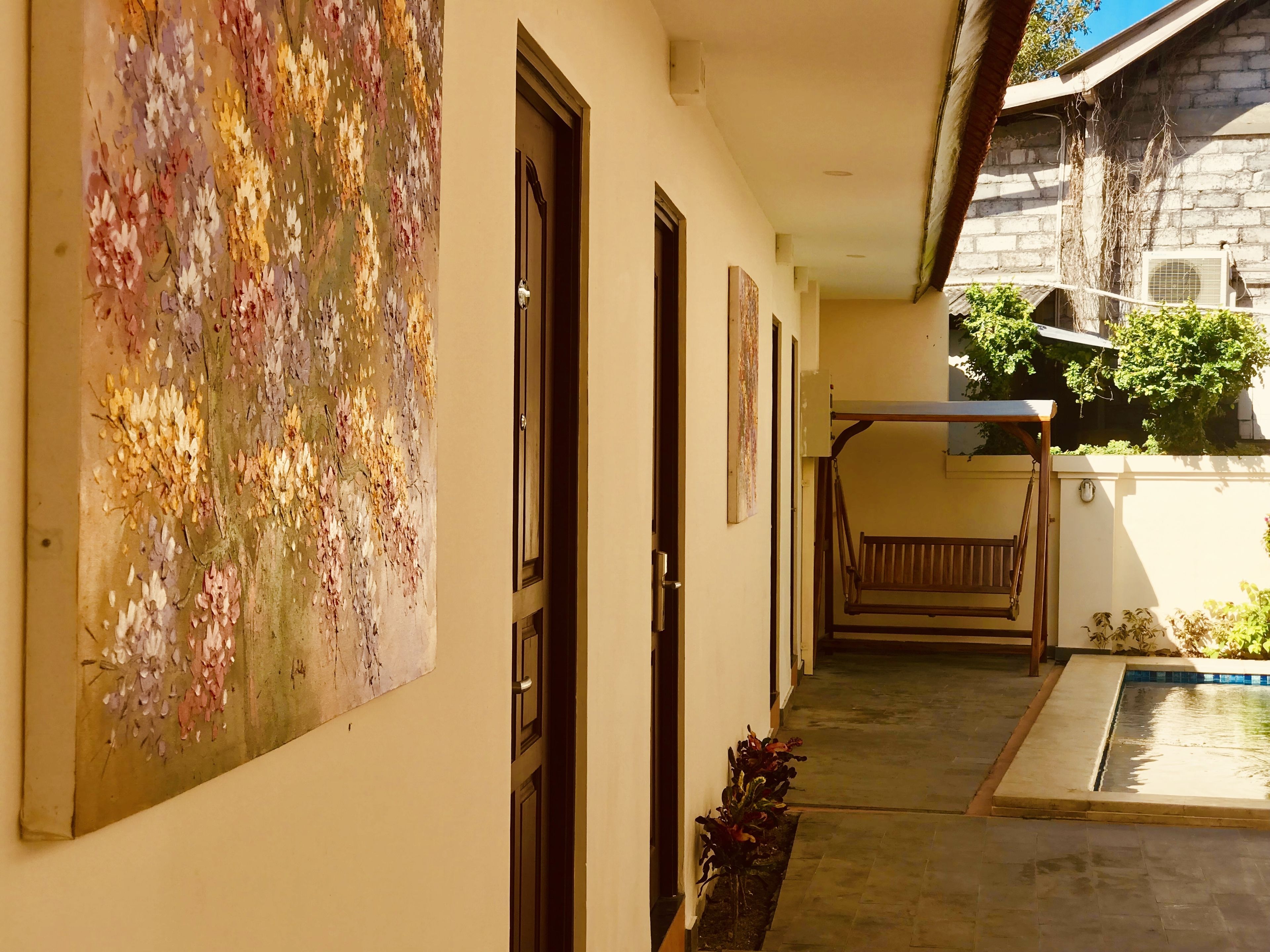 Un pasillo con un mural floral, puertas y un pequeño área de piscina.