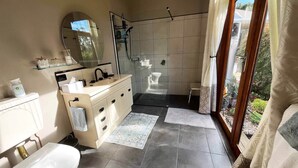 Uma casa de banho moderna com chuveiro, sanita e lavatório.