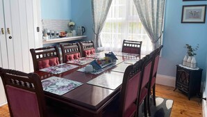 Uma sala de jantar com uma mesa de madeira posta para seis pessoas, rodeada por cadeiras estofadas.