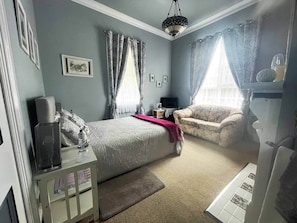 Une chambre à coucher avec un lit, un canapé, une télévision et un lustre.