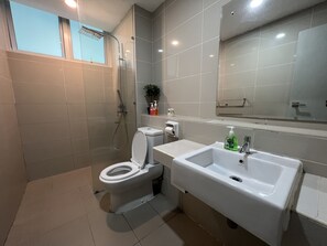 A modern bathroom with a toilet, a shower, and a sink.