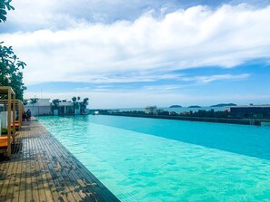 A swimming pool with a wooden deck and a view of the sea and distant islands.