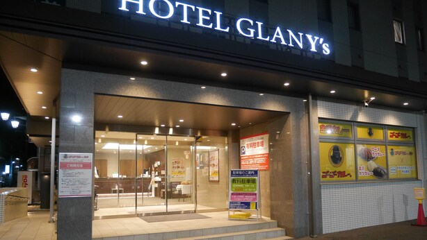 Hotel Glany's entrance with a glass door, a reception desk inside, and several signs advertising services and amenities. - HOTEL GLAN Y's KUMAGAYAEKIMAE premier (Kumagaya)