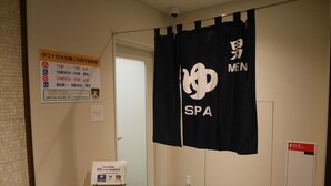 A men's spa area with a black curtain, a public bath sign, a hand sanitizer dispenser, and a cat-themed mat. - HOTEL GLAN Y's KUMAGAYAEKIMAE premier (Kumagaya)