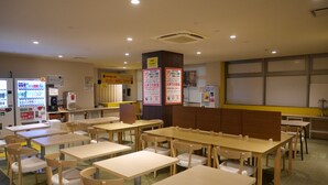 A dining area with multiple tables and chairs, vending machines, and informational posters on the walls. - HOTEL GLAN Y's KUMAGAYAEKIMAE premier (Kumagaya)