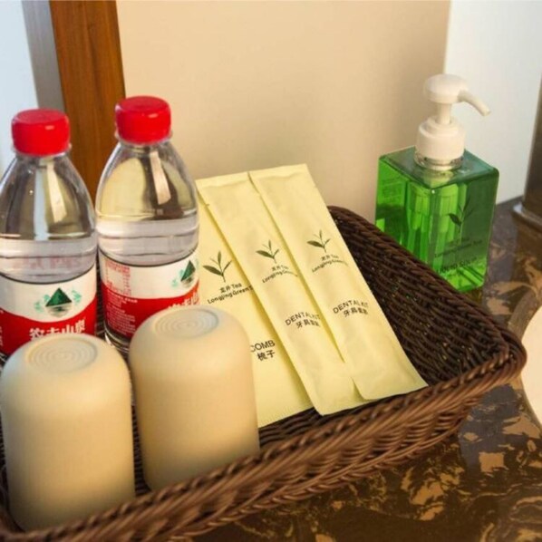 A wicker basket containing three bottles of liquid, two with red caps and one with a white cap, and a green bottle with a white pump.