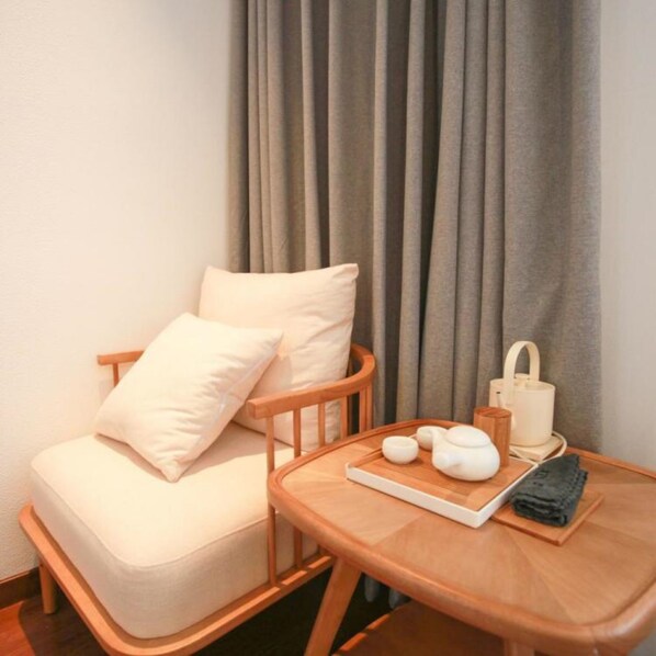 A cozy room with a wooden chair and a small table, featuring a teapot, cups, and a book.
