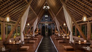 A dining area with tables, chairs, and hanging lights, featuring a wooden ceiling and large windows. - Kuwarasan A Pramana Experience (Tegallalang)