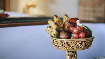 Un panier de fruits est posé sur une table, et il contient des bananes, des raisins et une pastèque.