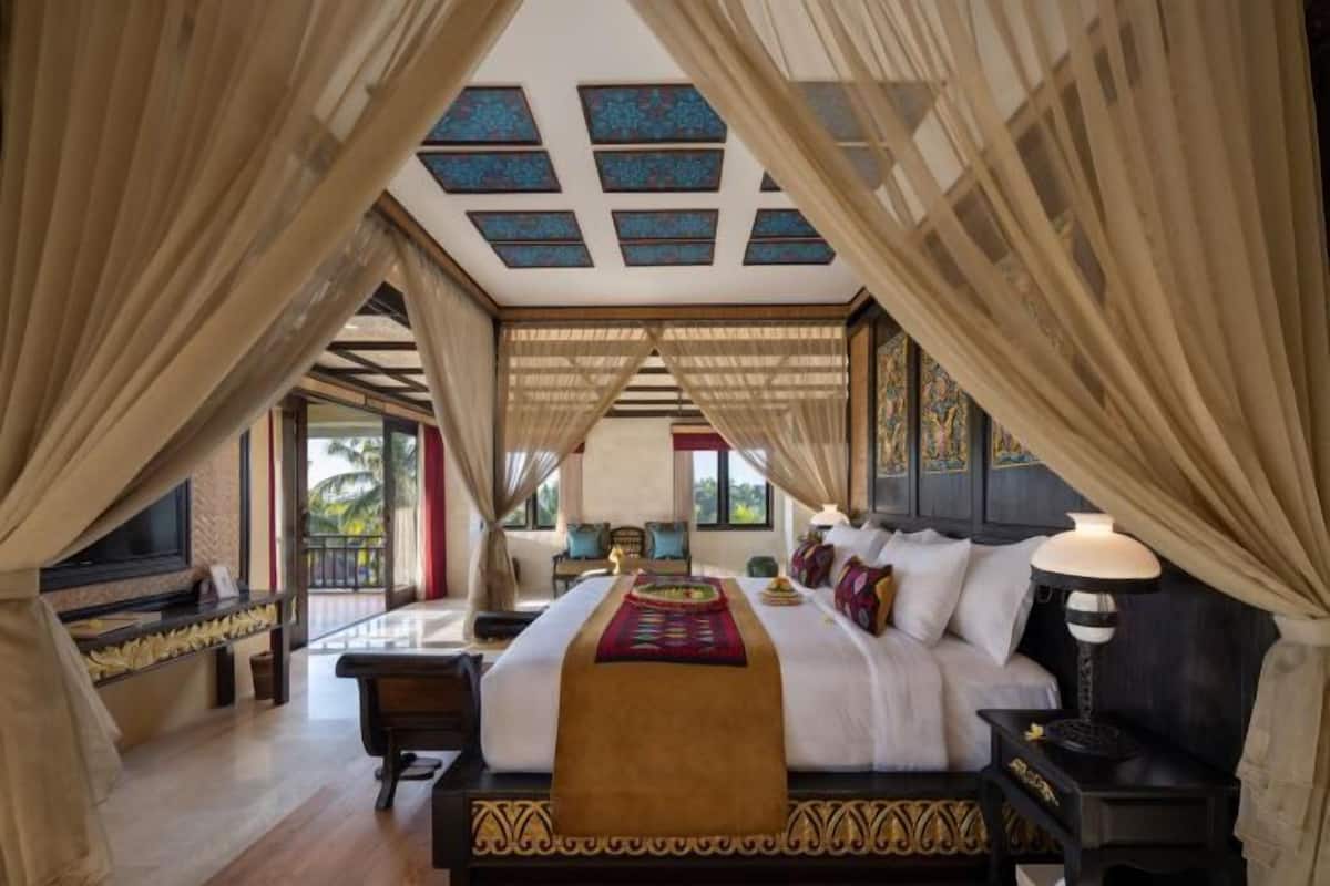 A bedroom with a large bed, curtains, a nightstand, and a TV.
